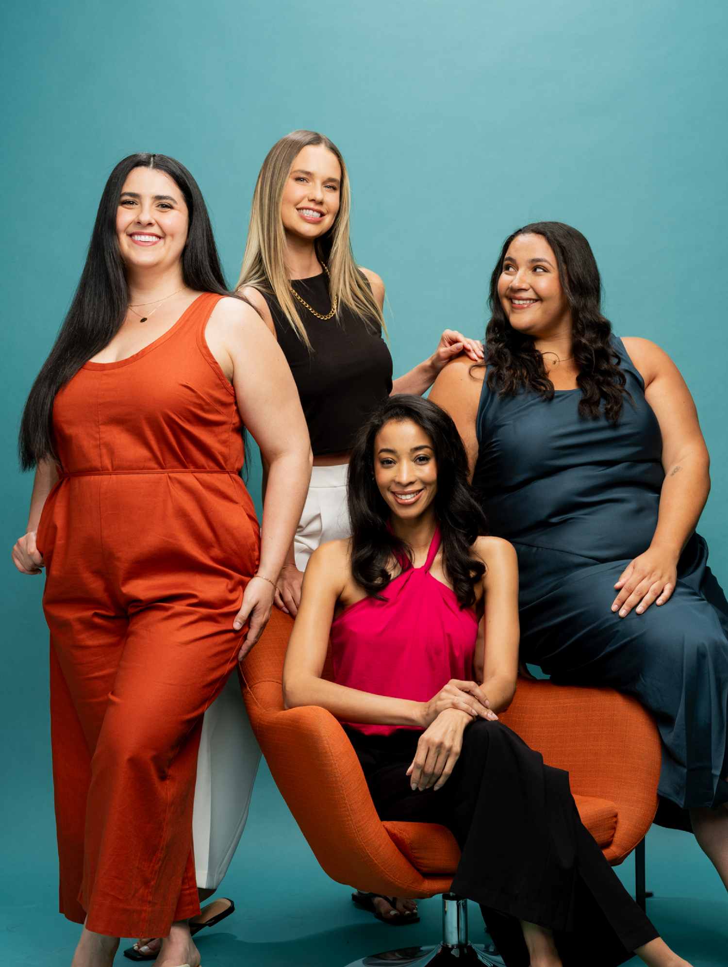Diverse group of four women in stylish clothes pose together after using the RevAir dryer. Their hair is now stretched longer and straighter.