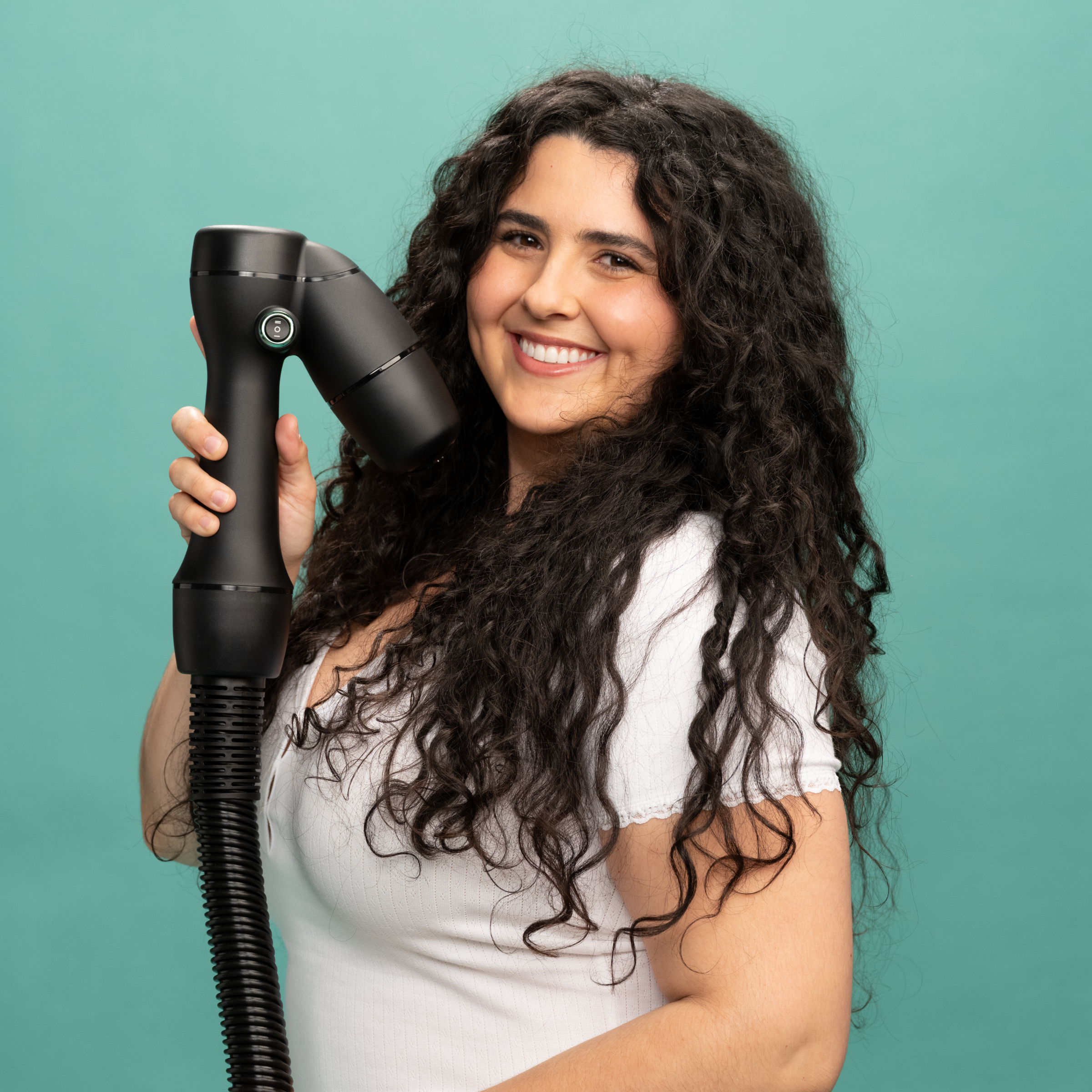Curly-haired woman smiling and holding up the RevAir wand