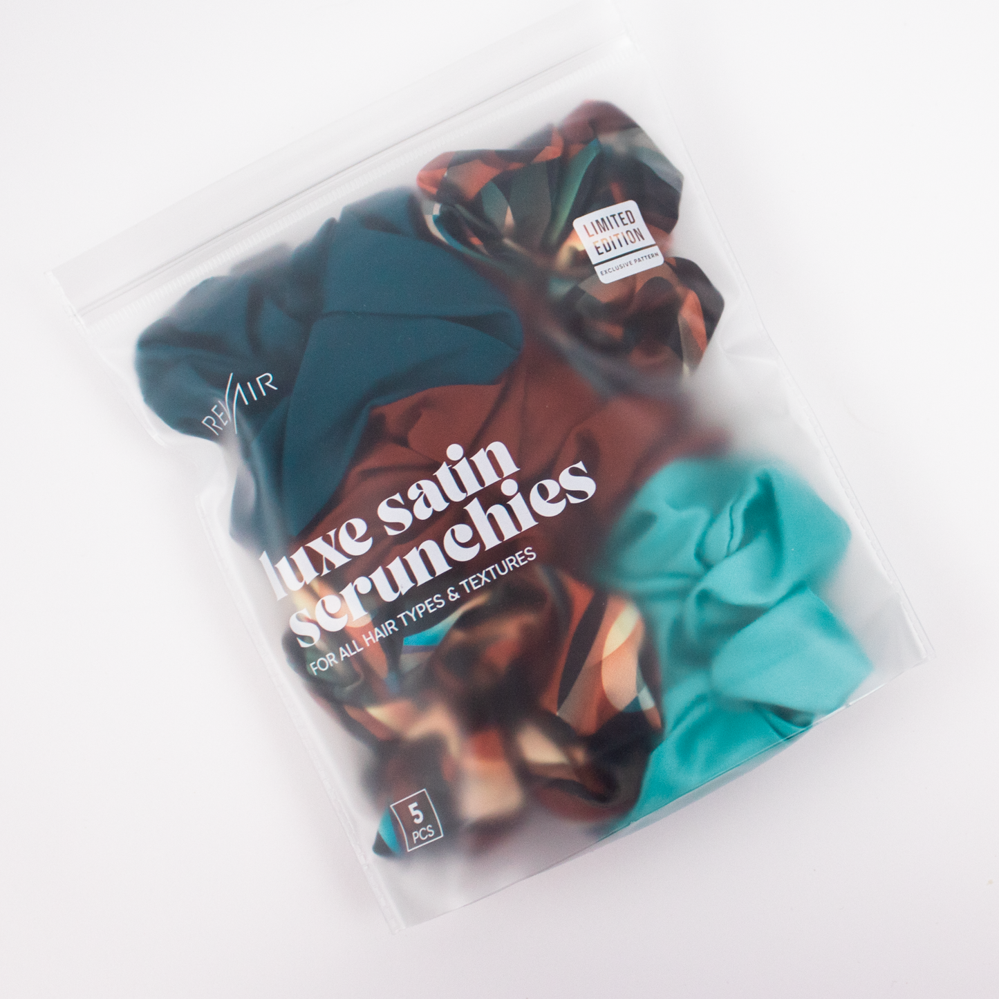 Packaged satin scrunchies with a limited edition label on a white background