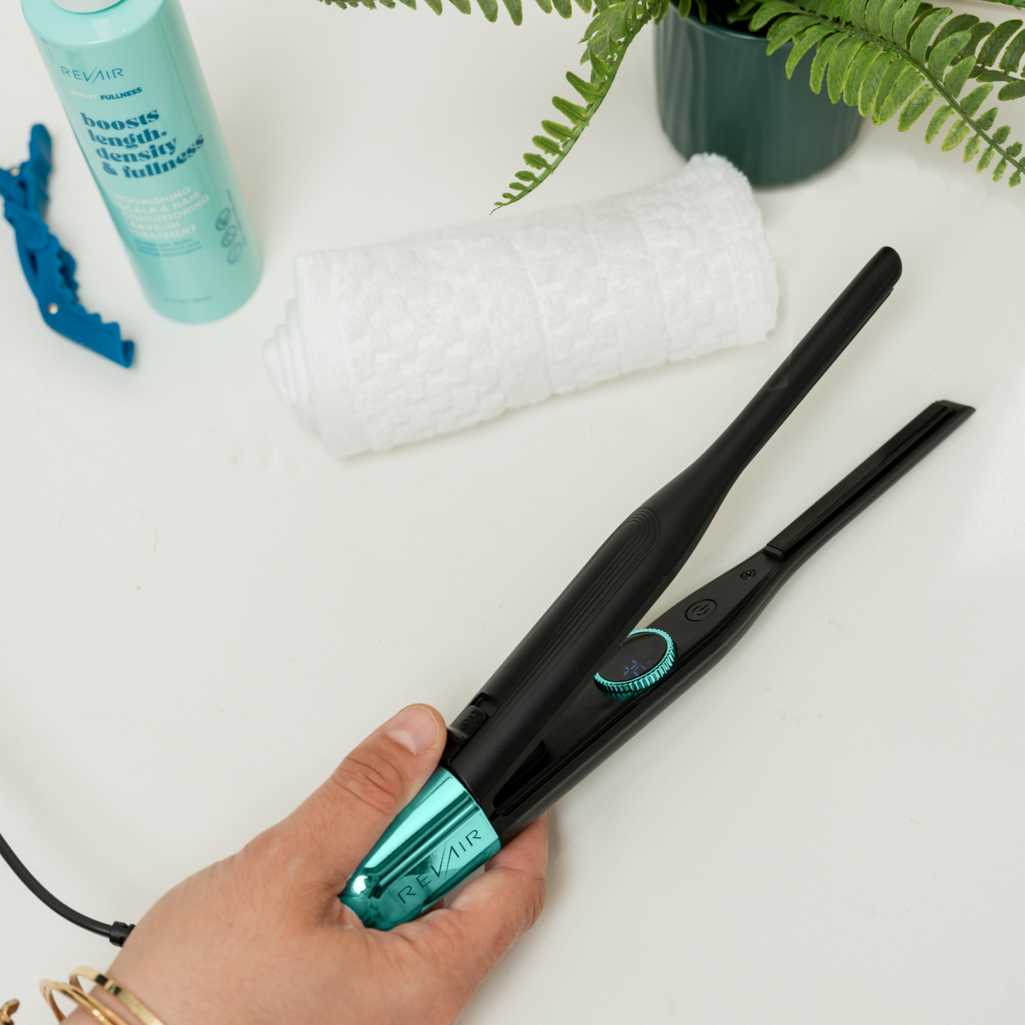 RevAir Micro Edge Styler ergonomic flat iron being held above bathroom counter, compact design for detail styling.
