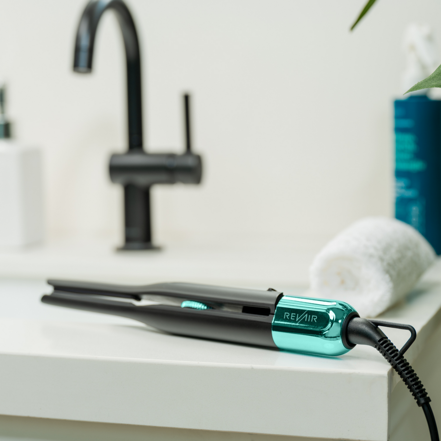 RevAir Micro Edge Styler pencil straightener on bathroom counter, sleek black and teal design with digital temperature control.