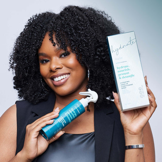 Woman with type 4 hair smiling and holding up RevAir extreme hydration products