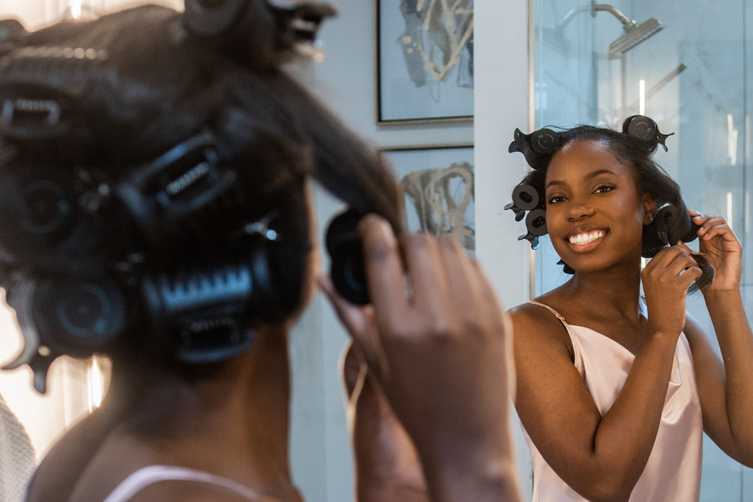 Woman removing a RevAir Amplifying Hot Roller while styling her hair in front of a bathroom mirror