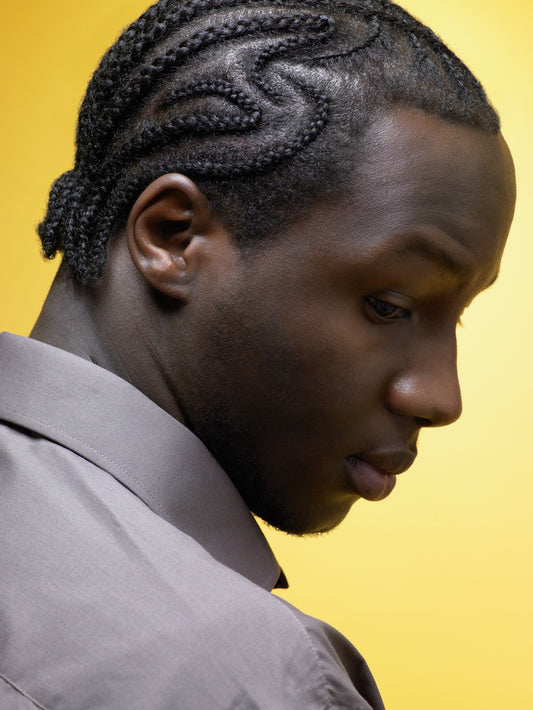 man-with-cornrow-braids-in-a-yellow-background