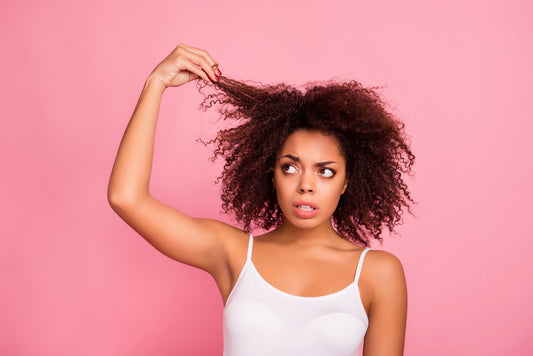 woman-holding-while-examining-her-damaged-hair-on-pink-background