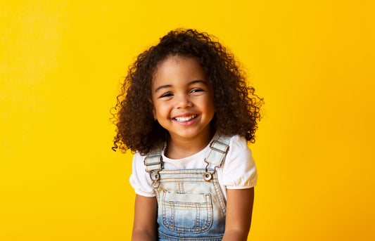 smiling-girl-child-with-natural-curly-hair-in-a-yellow-background