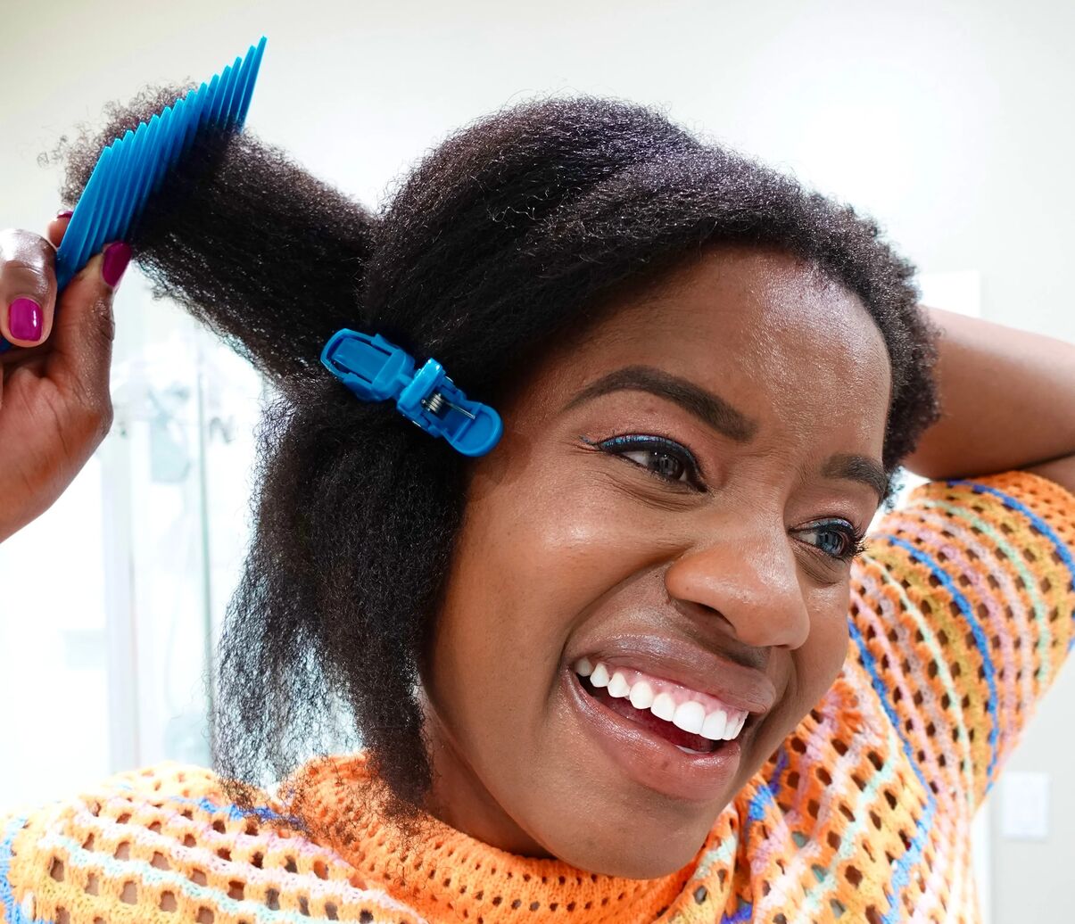 Woman smiling while using the Wright Comb to detangle her hair