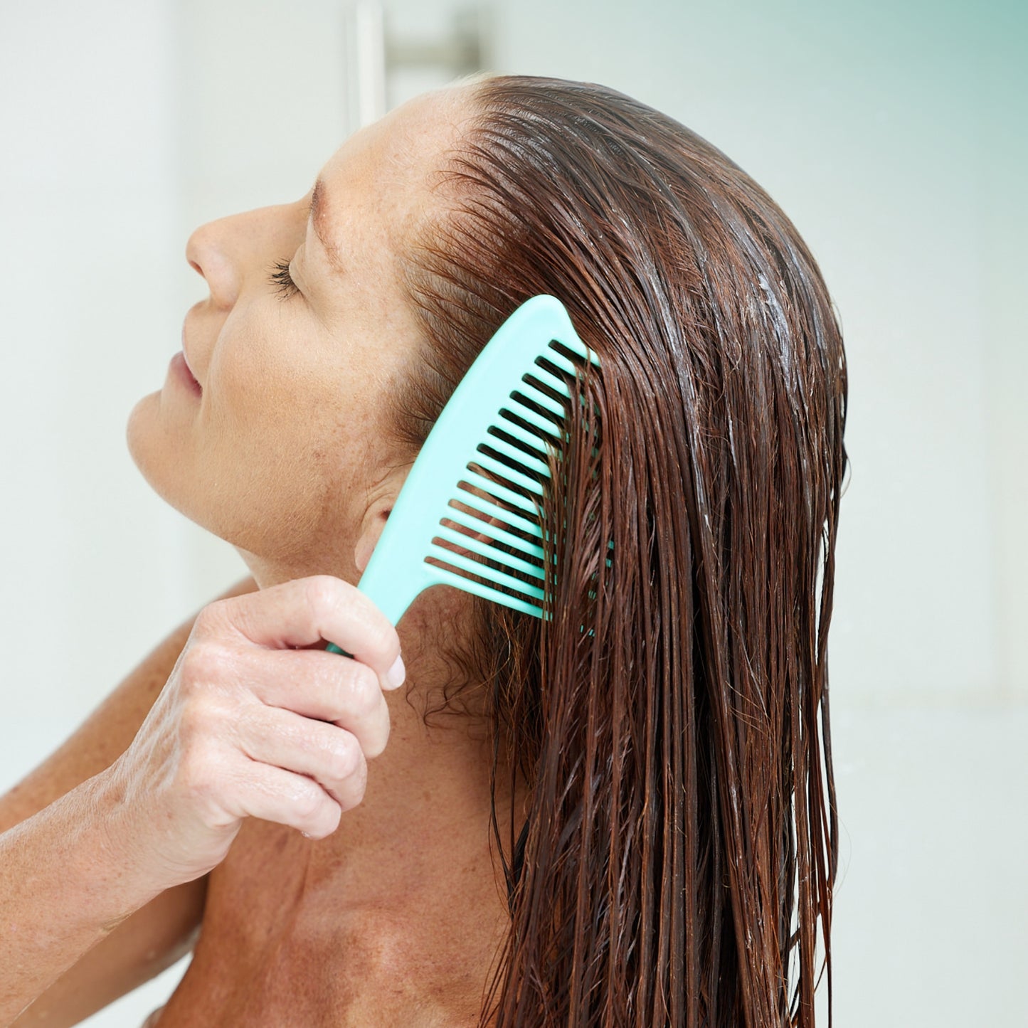 Woman combing RevAir conditioner through her wet hair
