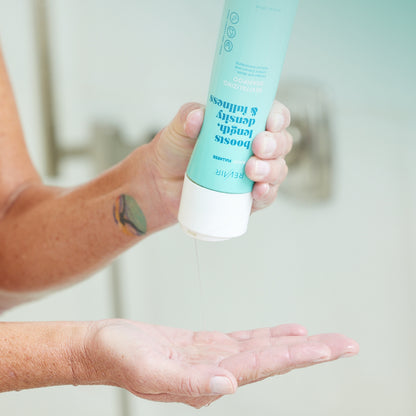 Woman in shower squeezing revitalizing shampoo onto hand