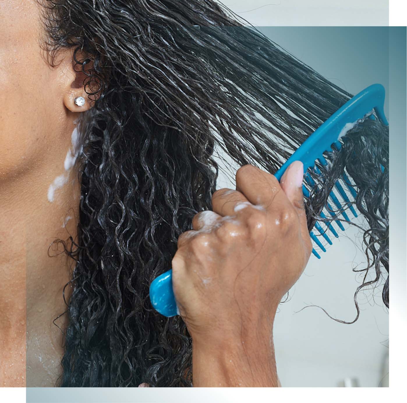 Woman with wet curly hair combing product through hair