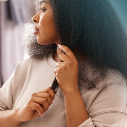 Woman working moisture-rich hair and scalp oil through her hair