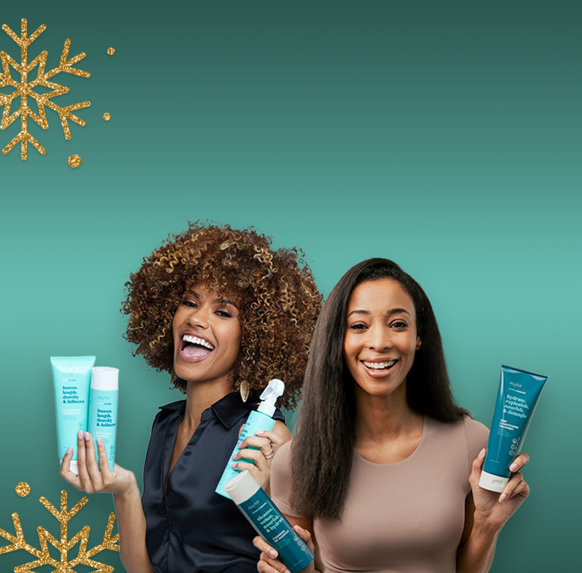 Two smiling women holding hair care products against a teal background with gold snowflakes