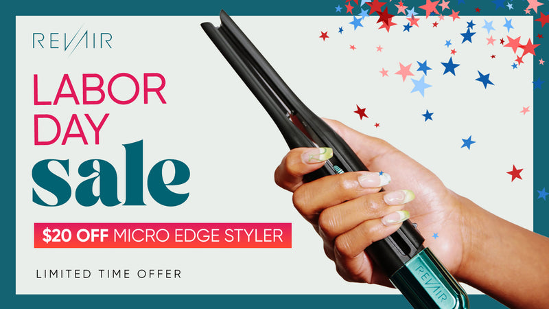 A hand holding a black REVAIR Micro Edge Styler flat iron during a Labor Day sale promotion with red, white, and blue star confetti on a white background.