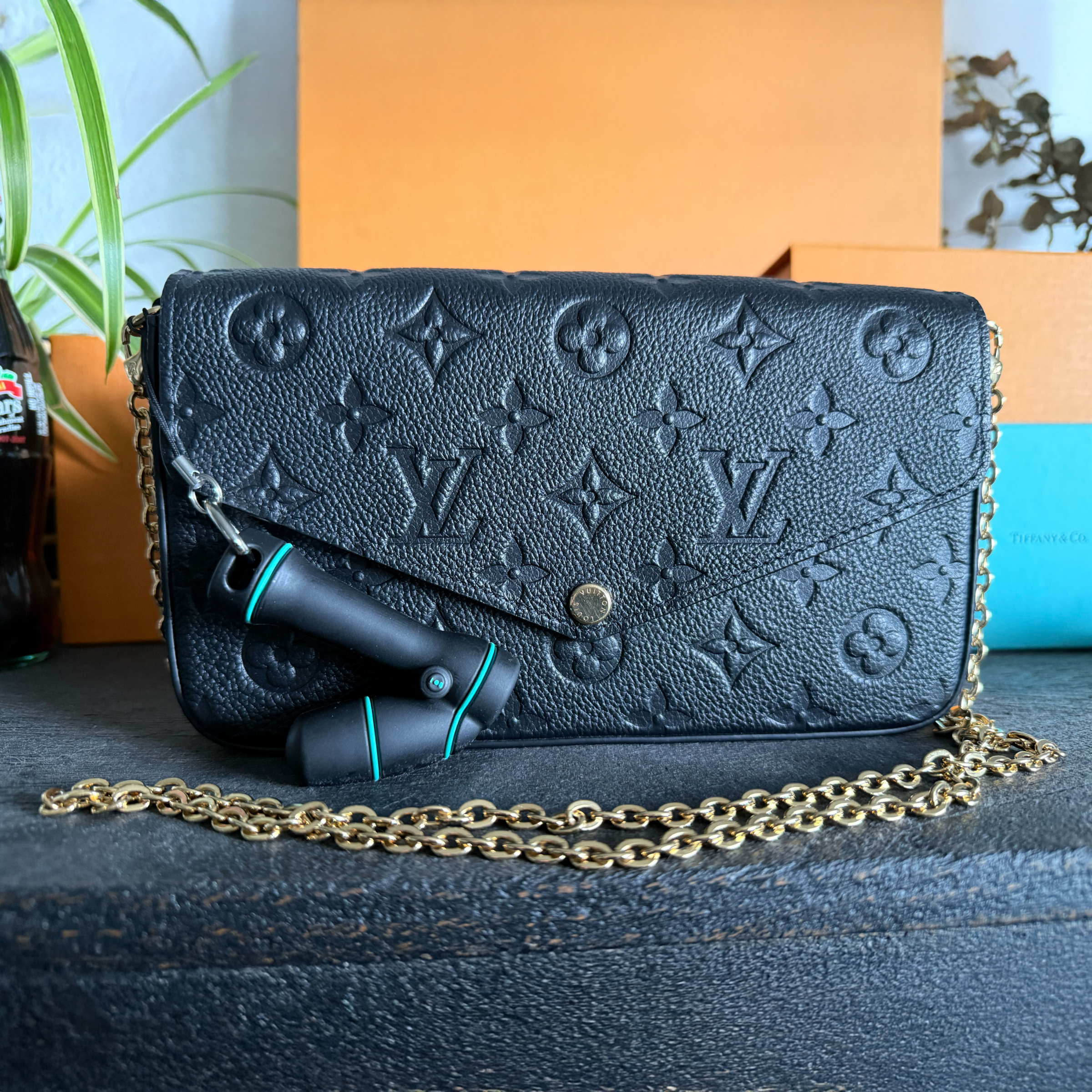 Mini wand bag charm shown clipped to a Vuitton chain wallet